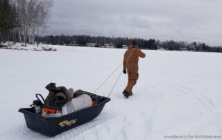 Angler drags sled filled with ice fishing equipment.