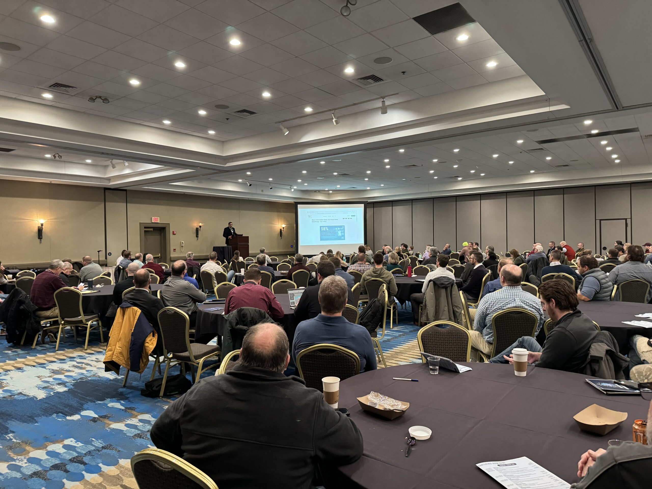 a conference center full of seated people watching a presentation